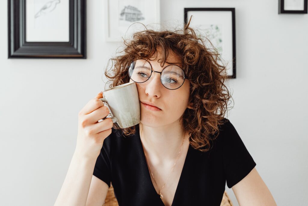 Photo of a woman thinking about eating disorder thoughts with her coffee mug pressed to her face. 